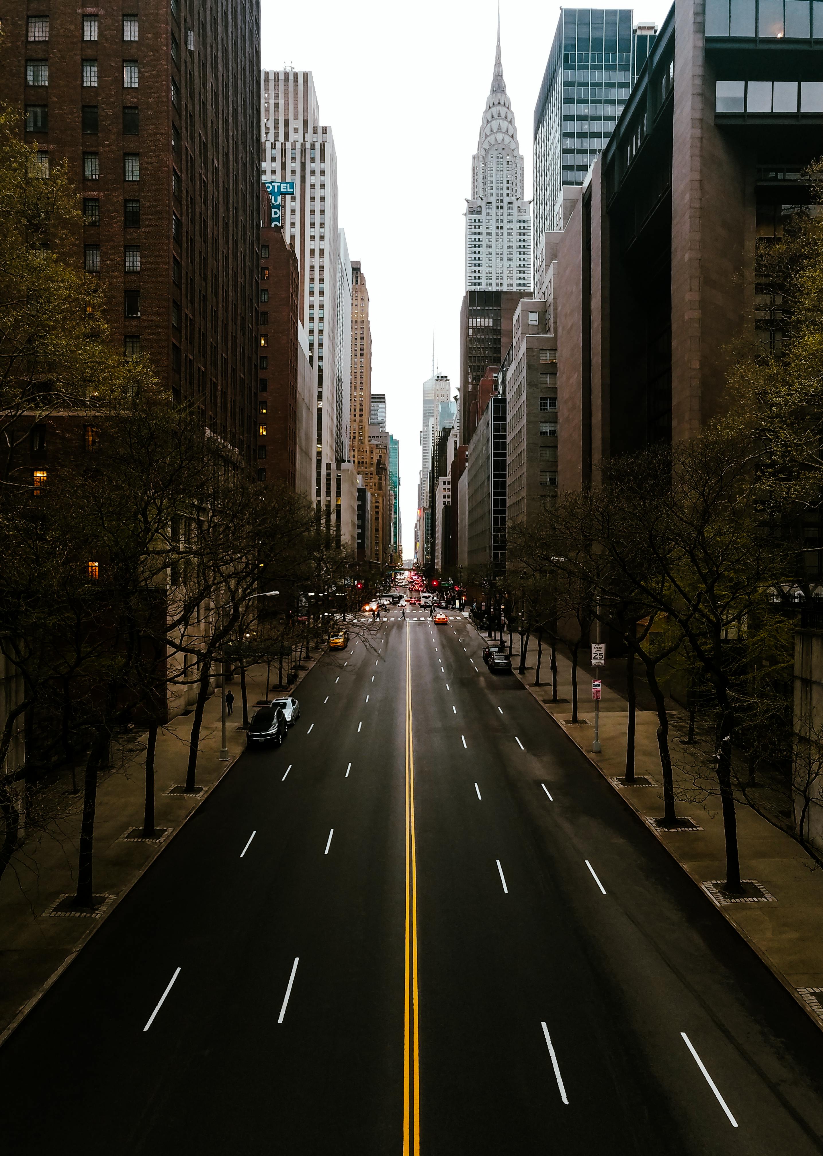 A view down a street in new york with lots of activity in the background but almost empty in the section closest to the camera